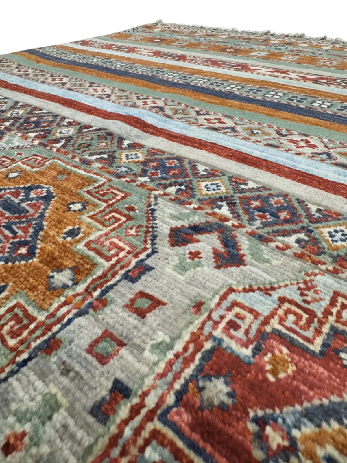 A vibrant Kazak Extra rug featuring intricate tribal designs in various colors, adding warmth to any space.