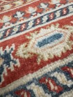 An oriental Kazak rug adorned with striking red, blue, and green patterns, exemplifying exquisite craftsmanship and beauty.