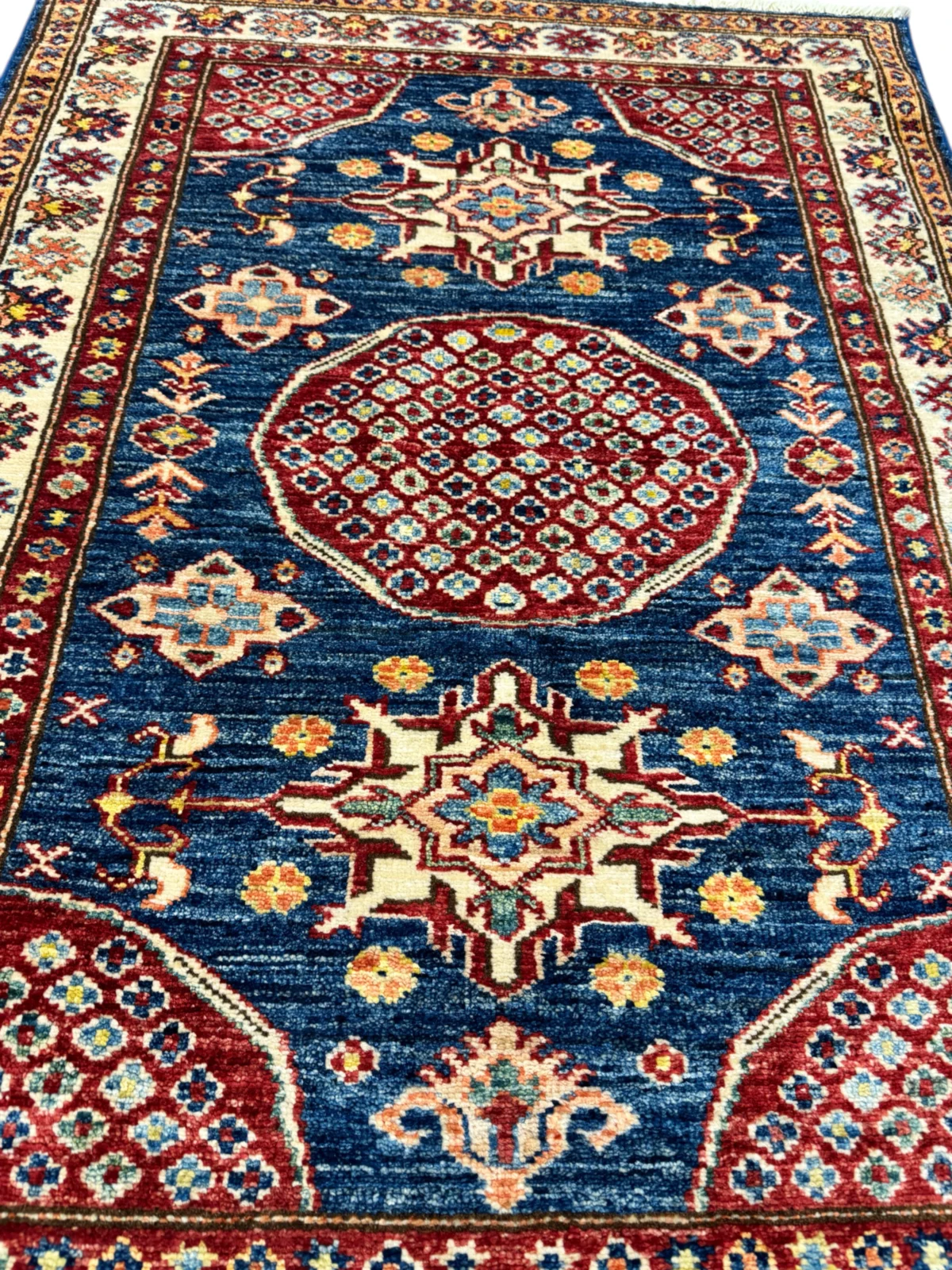 Tappeto Kazak blu e rosso, 124x88cm, un'opera artigianale in lana pregiata che porta calore e bellezza nella tua casa.