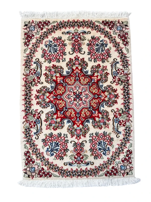 Tappeto Qum Extra qualità persiano 88x62 cm su fondo crema con medaglione rosso e blu, motivi floreali multicolore e frange bianche